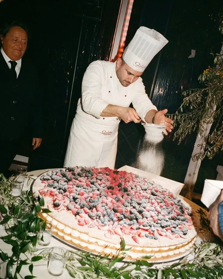 A chef dusting a berry pavlova at a wedding dinner