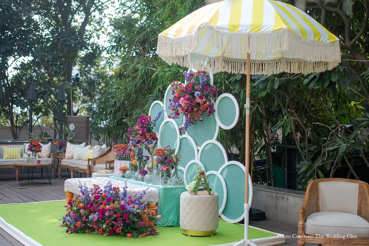A striped parasol and colourful floral lounge at a daytime Mehendi