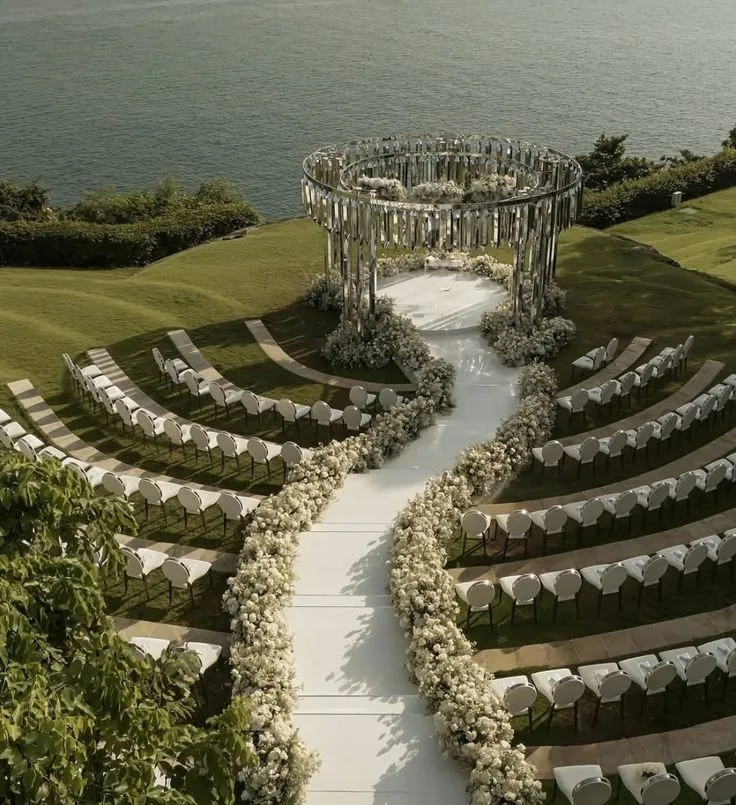 A circular seaside ceremony with a curving floral aisle